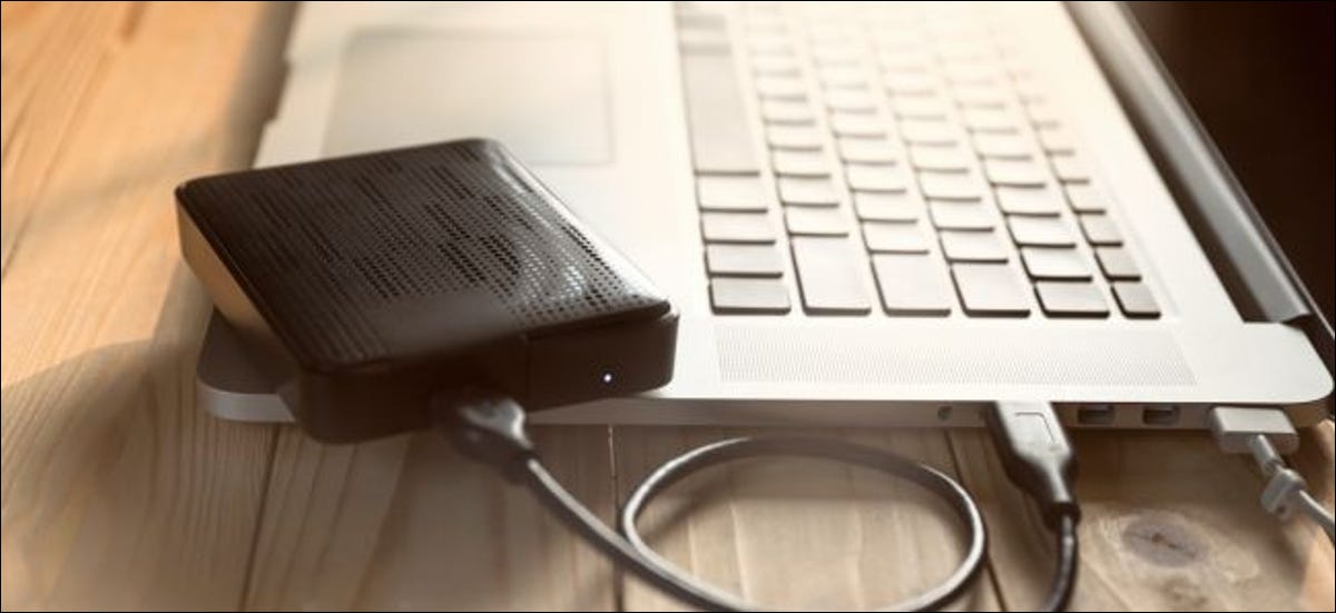 Ordenador portátil con pantalla en blanco que se conecta al disco duro externo negro