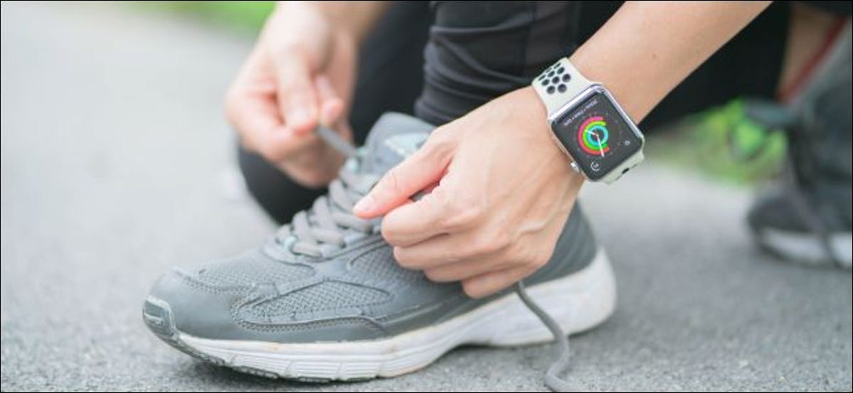 Una persona che allaccia i lacci delle scarpe e indossa un Apple Watch.