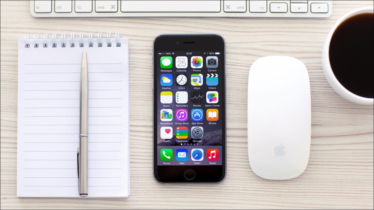 Un iPhone junto a un mouse y un teclado inalámbricos.