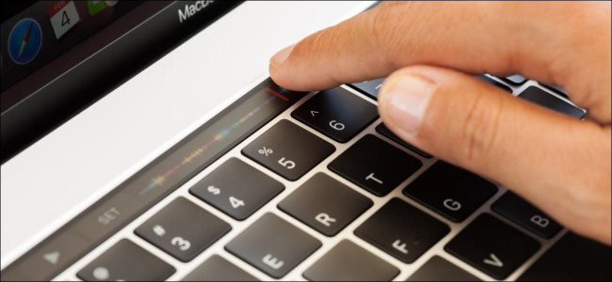 Una mano tocando la barra táctil en un MacBook Pro.