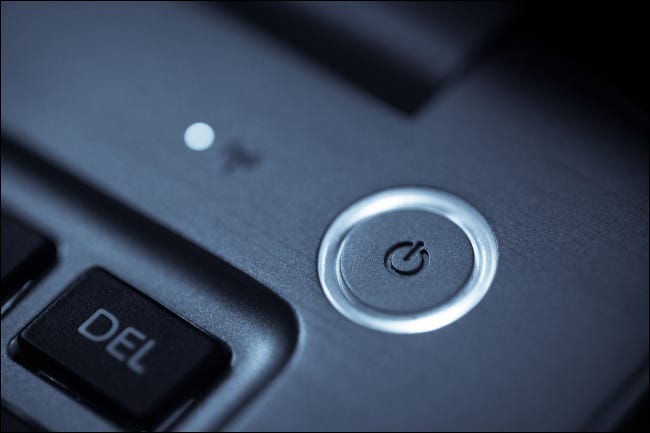 Primer plano de un botón de encendido redondo en la esquina de un teclado de computadora portátil.