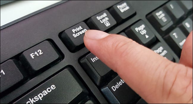 Un dedo presionando la tecla Imprimir pantalla en un teclado.