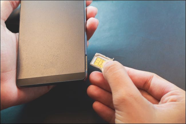Una mano insertando una tarjeta SIM en un teléfono inteligente.